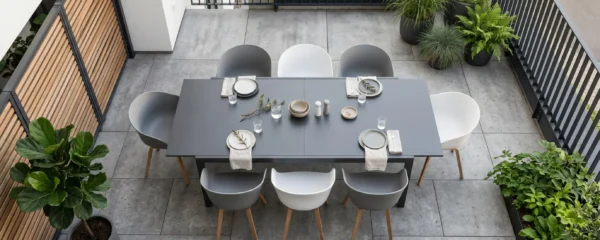 Vue en plongée d'une terrasse contemporaine avec table aluminium extensible, chaises assorties et décoration minimaliste